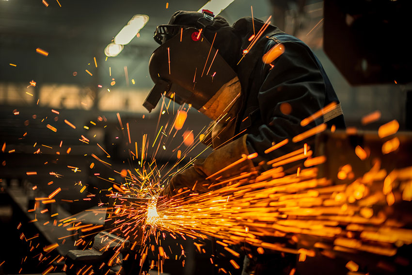 Worker welding with sparks flying - Fire Retardant vs. Flame-Resistant